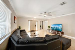 uma sala de estar com um sofá de couro preto e uma televisão de ecrã plano em Walk to Hollywood Beach Luxury 4BR Villa em Hollywood