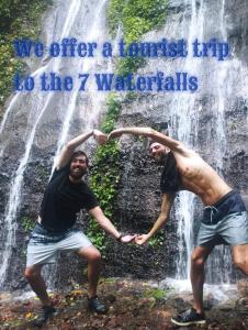 two men are standing in front of a waterfall at Juayúa Hostel & Tours,& Scooter in Juayúa