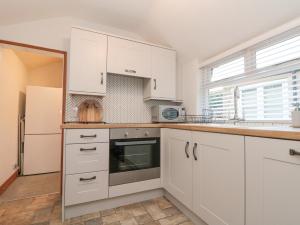 a kitchen with white cabinets and a sink and a refrigerator at Bay Tree Cottage in Pickering