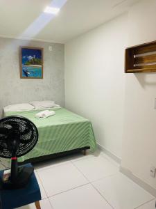 una camera con letto verde e ventilatore di Pousada hostel praia itapua a Salvador