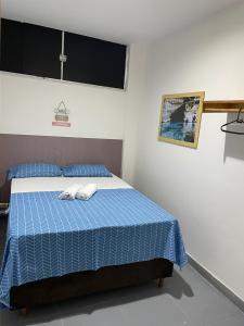 a bedroom with a blue bed with two towels on it at Pousada hostel praia itapua in Salvador