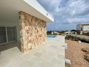ein Gebäude mit einer Steinmauer und einem Pool in der Unterkunft Villa Islander in Cala Morell