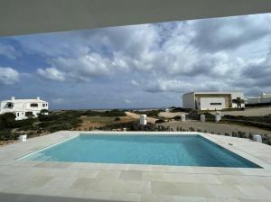 - une piscine avec vue sur une maison dans l'établissement Villa Islander, à Cala Morell