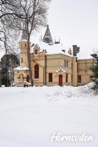 un bâtiment recouvert de neige devant une cour dans l'établissement Merlo Slott, à Timrå