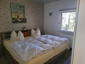 a bedroom with a bed with white sheets and a window at Waldblick in Marlow