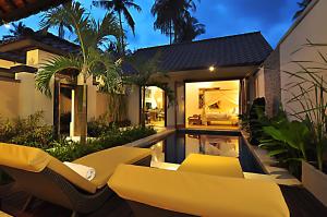 a backyard of a house with a swimming pool at night at Puri Mas Boutique Resort & Spa in Senggigi