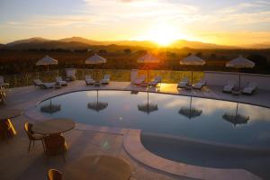 una piscina con sillas y mesas y la puesta de sol en Villa Agostina, en Murta Maria