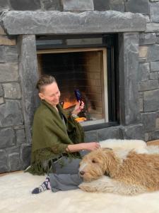 a man sitting next to a dog in front of a fireplace at Luxury suite with Sauna and Spa Bath - Elkside Hideout B&B in Canmore