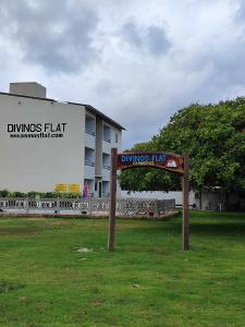 a sign in the grass in front of a building at Divinos Flat Carneiros in Praia dos Carneiros