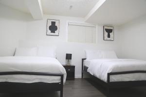 Duas camas num quarto com paredes brancas em Cozy Suite Near Airport Calgary em Calgary