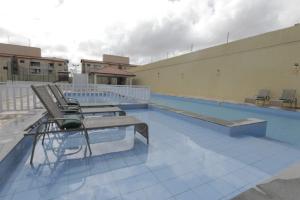 a swimming pool with chairs on the side of a building at Apartamento Luxuoso à 2km da Litorânea in São Luís