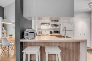 een keuken met witte kasten en een aanrecht met krukken bij Initial / Renard / MSA in Beaupré