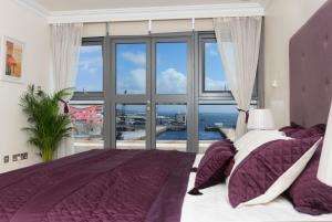 a bedroom with a purple bed and a large window at Luxury City Center Penthouse in Galway