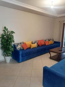 un sofá azul con almohadas coloridas en la sala de estar. en Lilac's Garden vue piscine en M'diq