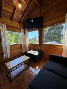 uma sala de estar com um sofá e duas janelas em Huilen de Bandurrias em San Martín de los Andes
