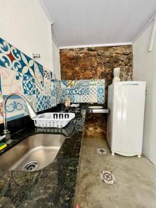 a kitchen with a sink and a refrigerator at CASINHA FLOR, no centro histórico!!! in Piranhas