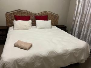 a large white bed with two red pillows and a pillow at Lux contractors accommodation in Bronkhorstspruit
