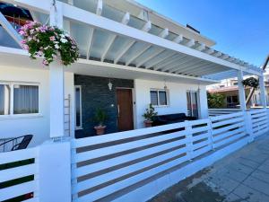 a white fence with a pergola on a house at Fat Cow Apartment 01 in Larnaka