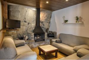 una sala de estar con 2 sofás y una chimenea de piedra. en Nastura Casa Rural L'Art, en Rupit