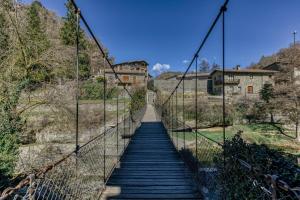 a suspension bridge over a river with a building in the background at Nastura Casa Rural L'Art in Rupit