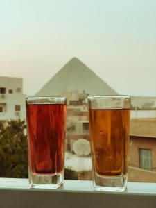 two glasses of beer sitting on a ledge with a pyramid at hermanos pyramids view in Cairo
