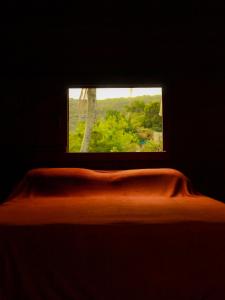 Valhalla Glamping House في بومبينهاس: نافذة في غرفة مظلمة مع سرير مع بطانية