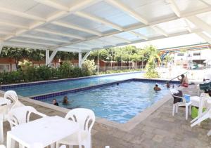 a swimming pool with white tables and white chairs at Caldas Novas DiRoma Fiori in Caldas Novas