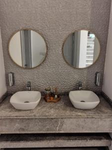 two sinks in a bathroom with two mirrors at La Vista Chalet in Billah