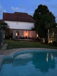 a swimming pool in front of a house at Hampton Oasis with Heated Pool & Large Garden in Molesey