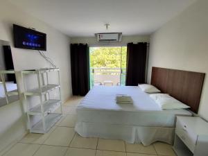 a bedroom with a large bed and a tv at Divinos Flat Carneiros in Praia dos Carneiros