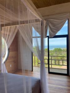 a bedroom with a canopy bed with a large window at Eco Boutique B&B in Punta Del Diablo
