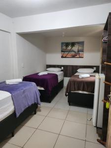 a hotel room with two beds with purple sheets at Hotel Pousada Farol de Manaíra in João Pessoa