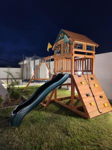 a wooden playset with a slide in the grass at La Vista Chalet in Billah