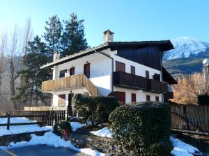 a large white house with a balcony in the snow at Le Coucou de Thovex in Morgex