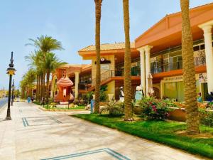 a building with palm trees in front of a street at Desert Pearl Romantic Apartment in Hurghada