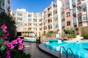 un grand immeuble avec un pont sur une piscine dans l'établissement Desert Pearl Romantic Apartment, à Hurghada