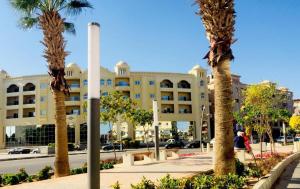 a building with palm trees in front of a street at Desert Pearl Romantic Apartment in Hurghada