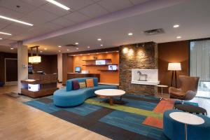 vestíbulo con sofá azul, mesas y sillas en Fairfield Inn & Suites by Marriott Edmonton North en Edmonton