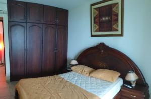 een slaapkamer met een bed met een houten hoofdeinde bij Departamento al pie del mar Torre Marina in Salinas