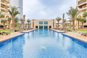 a large swimming pool with chairs and palm trees at GLOBALSTAY. Luxury 3 Bedroom + Maid Townhouse with Sea View in Dubai