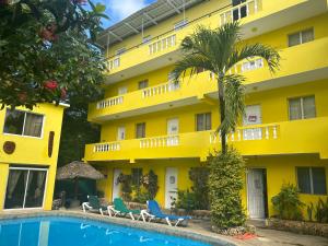 ein gelbes Gebäude mit einem Pool davor in der Unterkunft Coco Hotel and Hostel in Sosúa