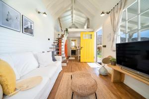 ein Wohnzimmer mit einem weißen Sofa und einem TV in der Unterkunft The Box House & Charming Private Tiny House & Pool in Göcek