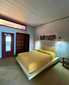 Un dormitorio con una gran cama amarilla con una pintura en la pared en AmimodoBeachRooms en Puerto Viejo