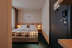 a hotel room with a bed with two lamps and a door at Alpina Hotel Gudauri in Gudauri