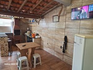a kitchen with a table and a tv on a wall at Cantinho do Rafa São Lourenço MG in São Lourenço