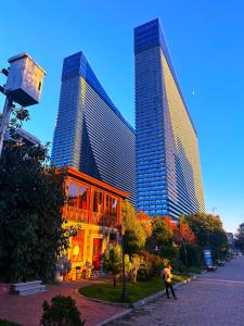 dois edifícios altos numa cidade com um homem a andar na frente em Orbi City Apartments em Batumi