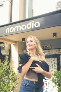a woman holding a black dog in front of a store at Nomadia Hostel Boutique in Bogotá