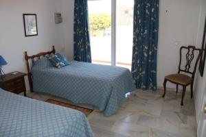 ein Schlafzimmer mit zwei Betten und einem Fenster mit Vorhängen in der Unterkunft Holiday Villa in Calahonda, near Marbella in Sitio de Calahonda