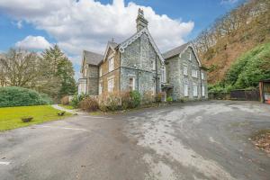 an old stone house with a driveway in front of it at 1 Brathay Fell in Ambleside