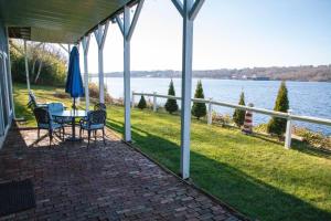 a porch with a table and chairs and a view of the water at Waterfront Home with a View in Groton